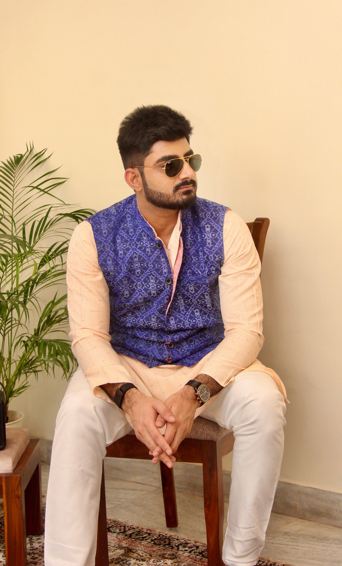 Shaam Savera reversible handloom jacket for men, blue ikat side worn over a cream kurta, seated