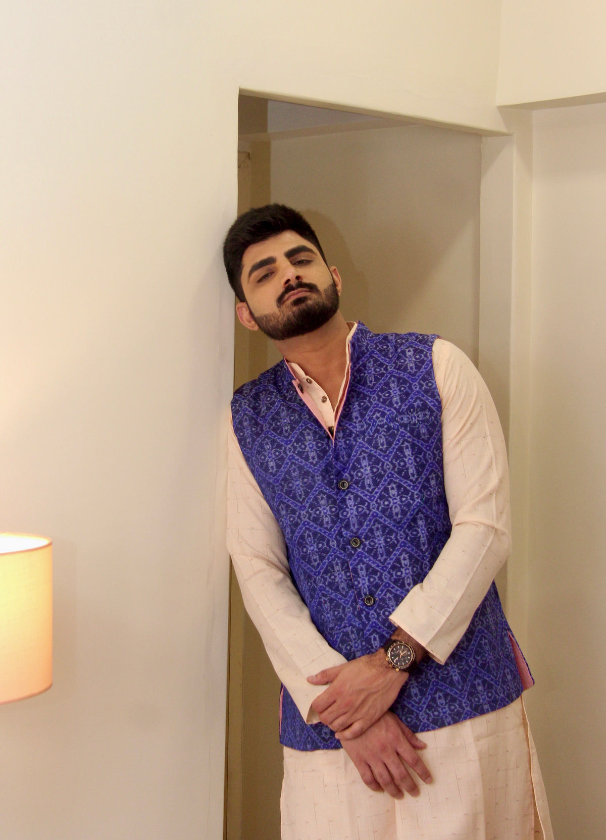 Shaam Savera reversible handloom jacket for men, blue ikat side worn over a cream kurta, standing