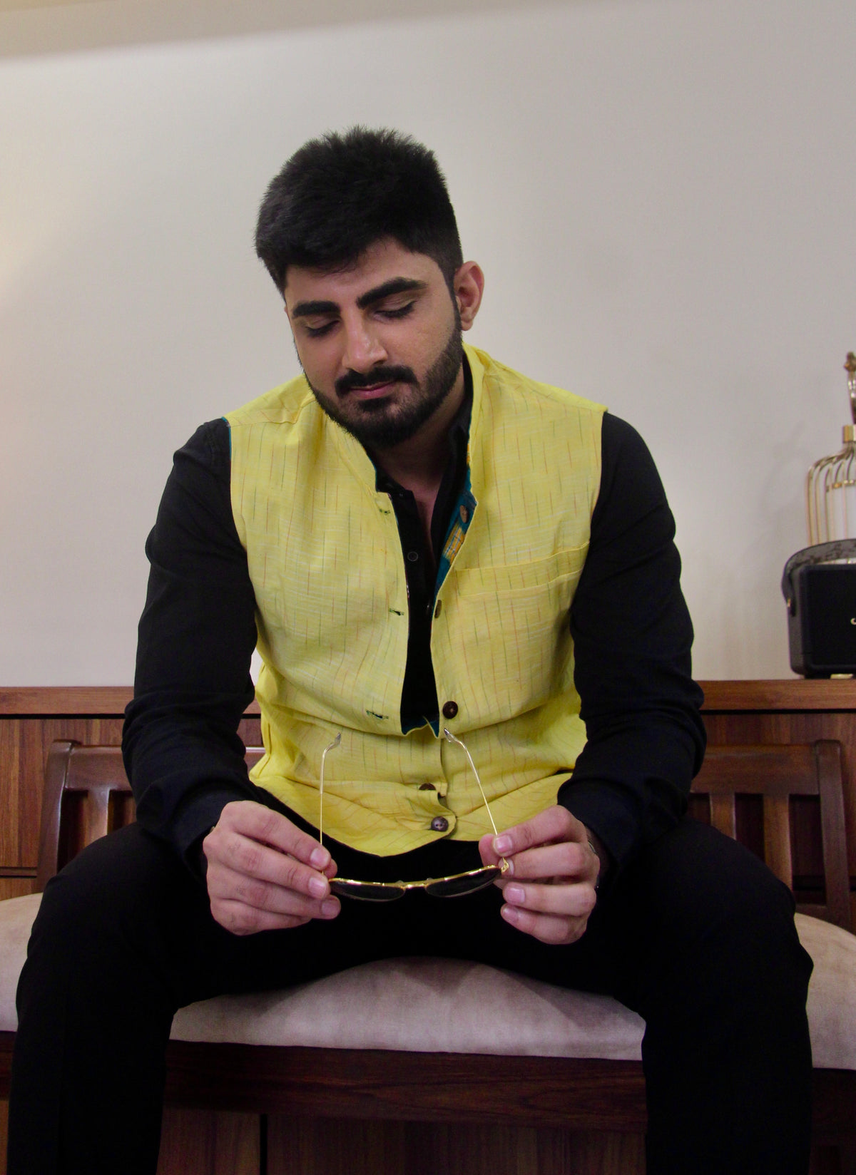 Kacchi Keri reversible handloom jacket for men, yellow reverse side worn over a black shirt, seated