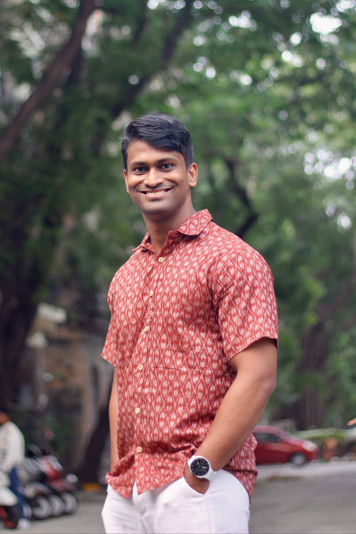 Maati brick red Nuapatna ikat handloom shirt for men worn with white trousers, front view